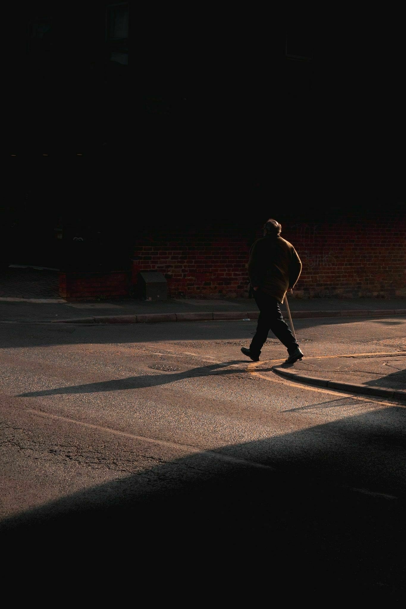 a man crossing the road been two shadows through a tunnel of light